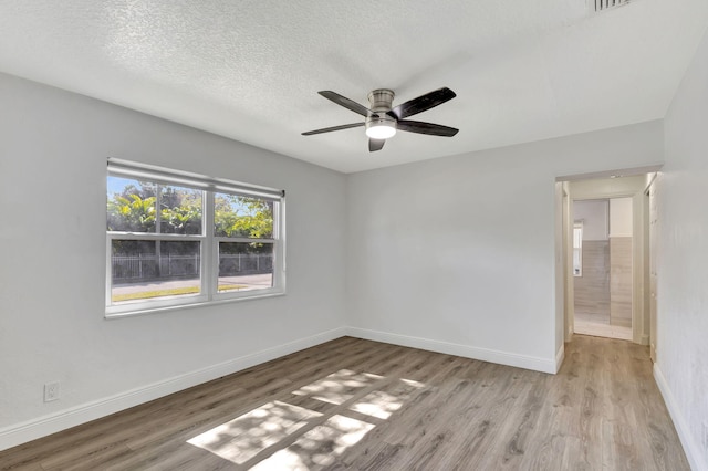 spare room with baseboards, a textured ceiling, a ceiling fan, and light wood-style floors