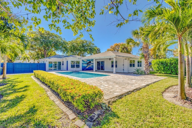 rear view of house featuring a patio, a fenced in pool, and a lawn