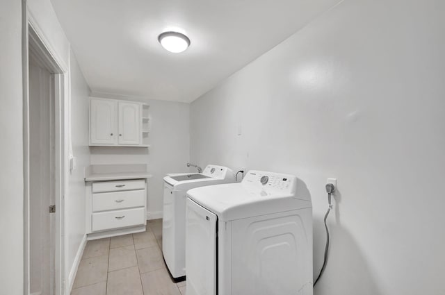 clothes washing area featuring cabinet space, light tile patterned floors, baseboards, and separate washer and dryer