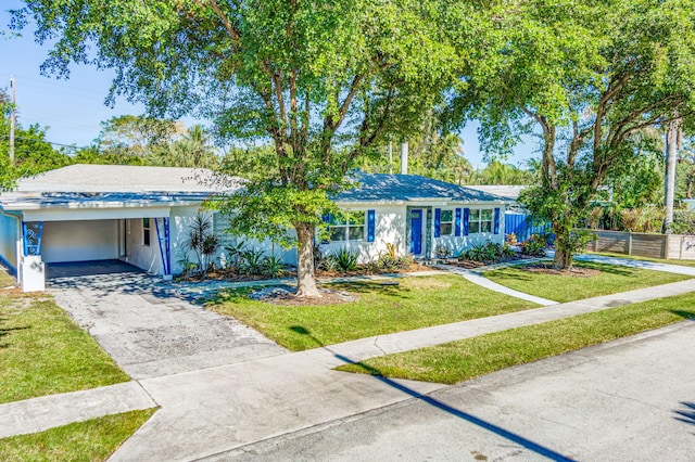 ranch-style home with stucco siding, concrete driveway, fence, a carport, and a front lawn