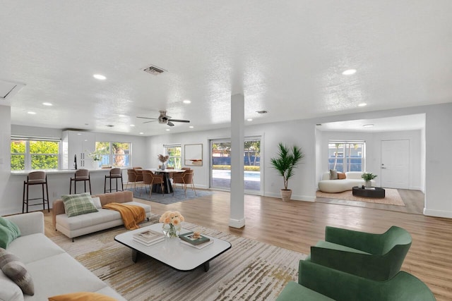 living area with visible vents, a textured ceiling, and light wood-style flooring