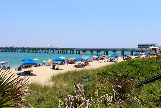 property view of water featuring a pier and a beach view