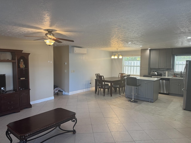 living room featuring a healthy amount of sunlight, ceiling fan with notable chandelier, a wall unit AC, and light tile patterned floors