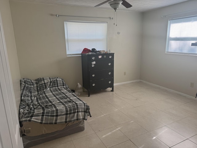 tiled bedroom with ceiling fan and a textured ceiling