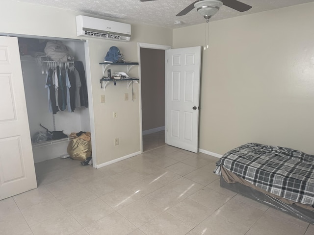 bedroom with a textured ceiling, an AC wall unit, a closet, and ceiling fan