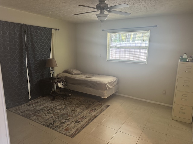 tiled bedroom with ceiling fan and a textured ceiling