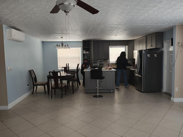 interior space with pendant lighting, black refrigerator, gray cabinetry, a center island, and a wall mounted AC