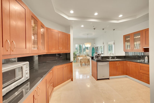 kitchen with dishwasher, decorative light fixtures, a tray ceiling, and sink