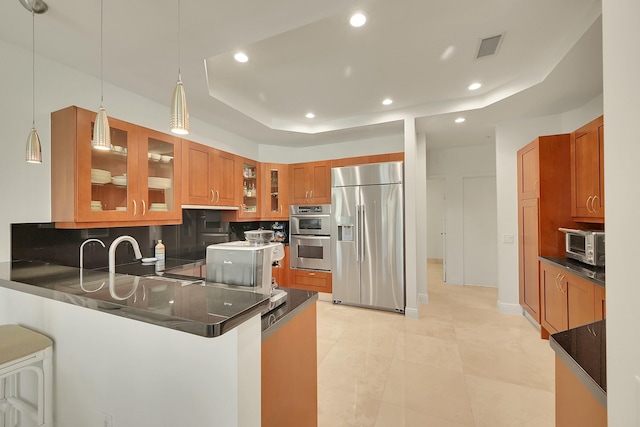 kitchen featuring a raised ceiling, sink, decorative light fixtures, kitchen peninsula, and stainless steel appliances