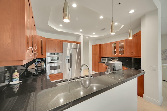 kitchen featuring a raised ceiling, tasteful backsplash, pendant lighting, and appliances with stainless steel finishes