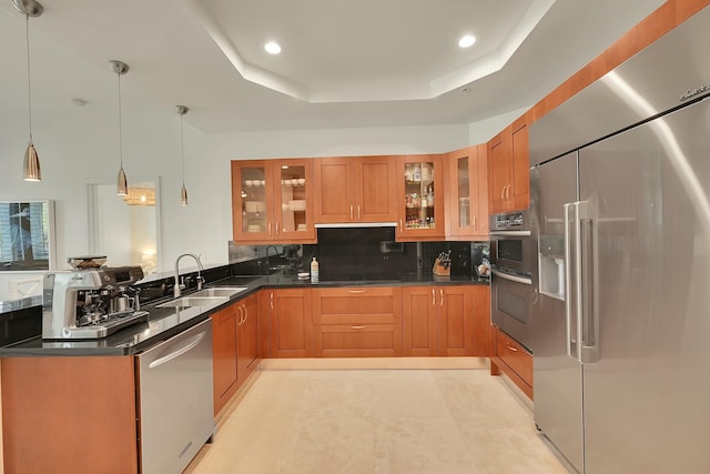 kitchen featuring pendant lighting, a raised ceiling, sink, decorative backsplash, and appliances with stainless steel finishes