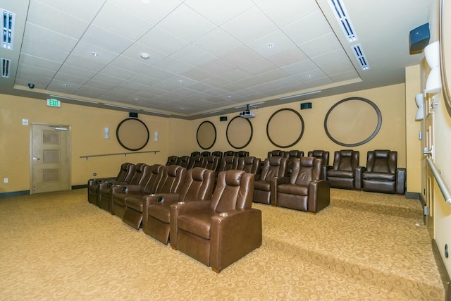 carpeted home theater room with a paneled ceiling and a raised ceiling