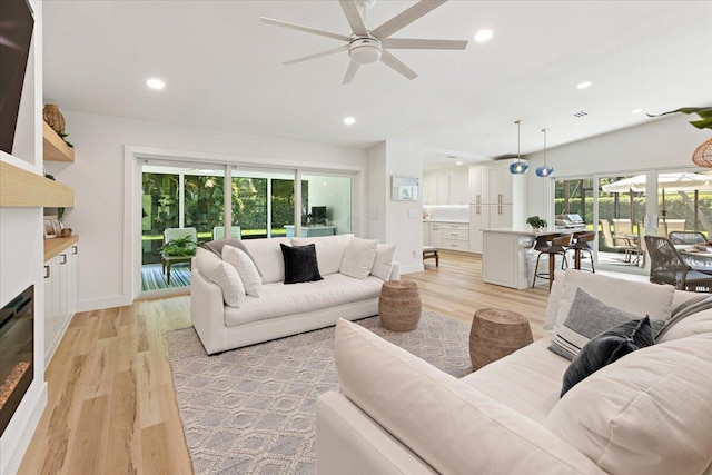 living room with ceiling fan, light hardwood / wood-style floors, and lofted ceiling