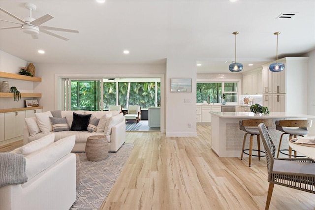 living room featuring a wealth of natural light, light wood-type flooring, and ceiling fan