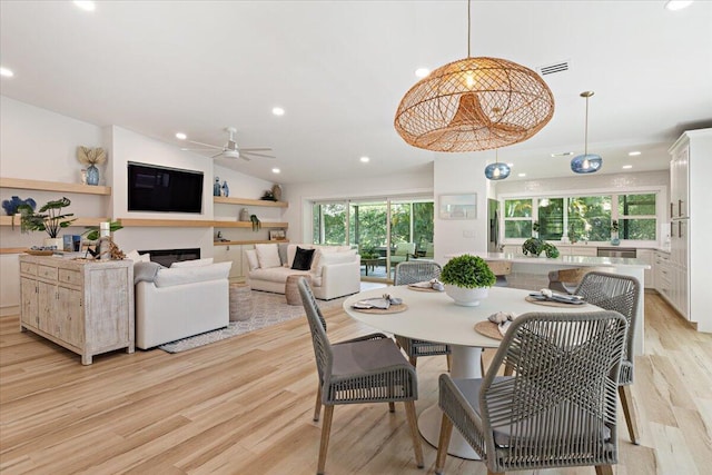 dining area featuring ceiling fan, lofted ceiling, and light hardwood / wood-style flooring