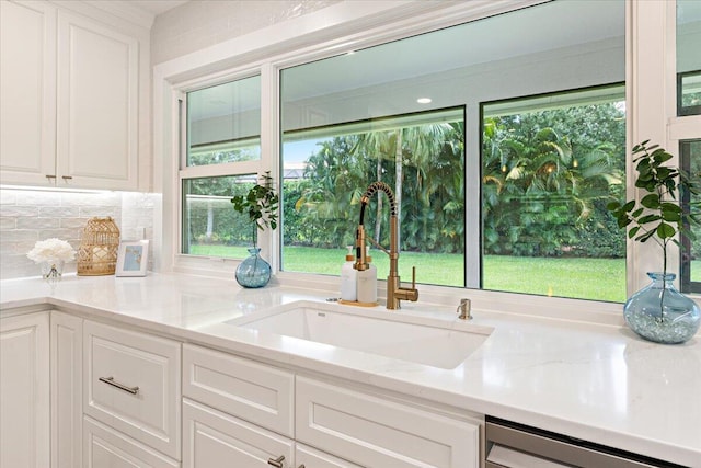 kitchen featuring white cabinets, light stone countertops, dishwasher, and sink