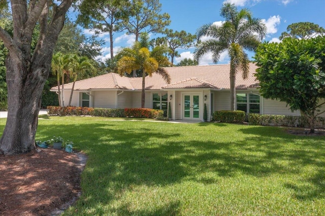 view of front facade featuring a tiled roof, french doors, and a front yard