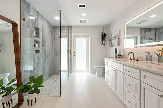 bathroom with toilet, vanity, and tiled shower