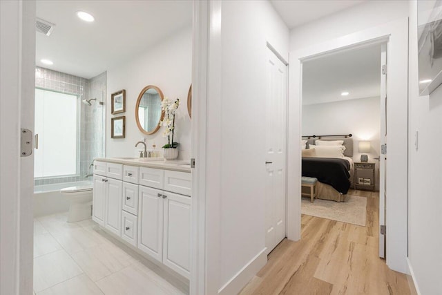 full bathroom with hardwood / wood-style floors, vanity, toilet, and tiled shower / bath