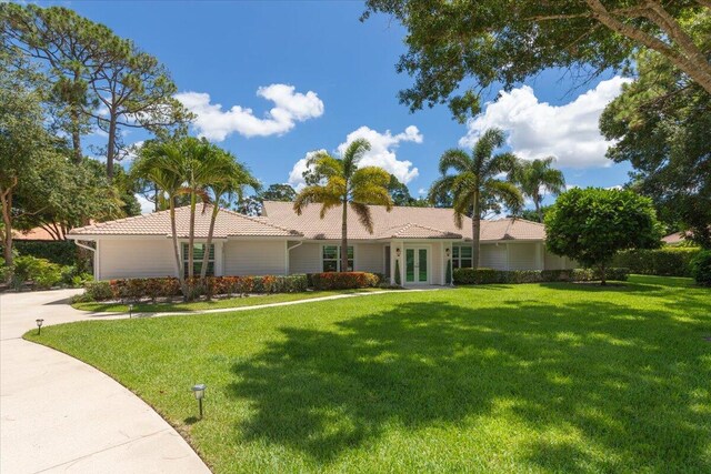single story home featuring french doors, a tiled roof, and a front lawn