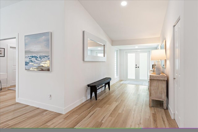 hall featuring vaulted ceiling, french doors, and light hardwood / wood-style flooring