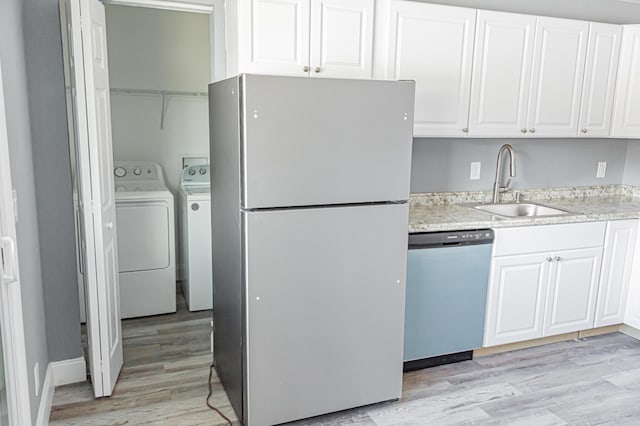 kitchen featuring washing machine and clothes dryer, white cabinetry, dishwasher, sink, and white fridge