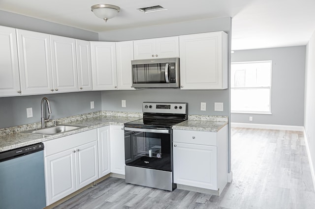 kitchen featuring sink, light stone countertops, light hardwood / wood-style floors, white cabinetry, and stainless steel appliances