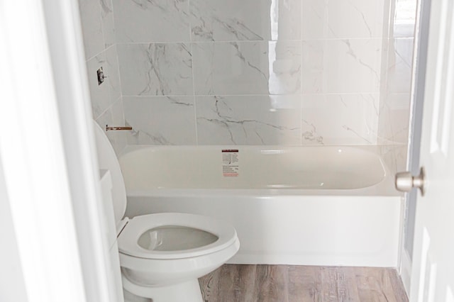 bathroom with hardwood / wood-style floors, toilet, and a tub