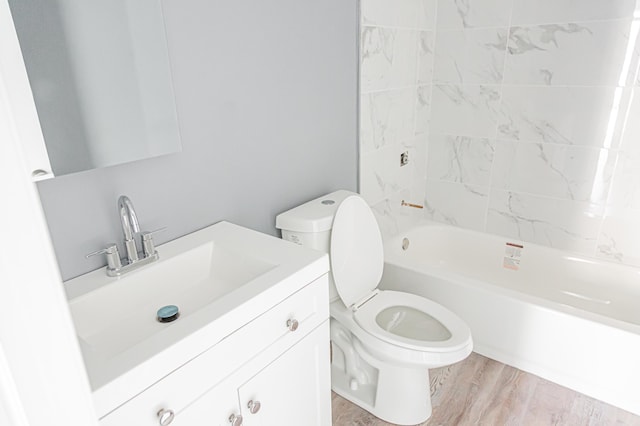 full bathroom featuring tiled shower / bath, hardwood / wood-style flooring, vanity, and toilet