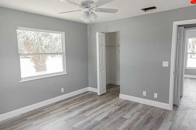 unfurnished bedroom with multiple windows, ceiling fan, a closet, and light wood-type flooring