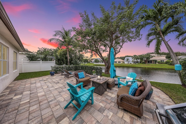 patio terrace at dusk featuring a water view and an outdoor fire pit