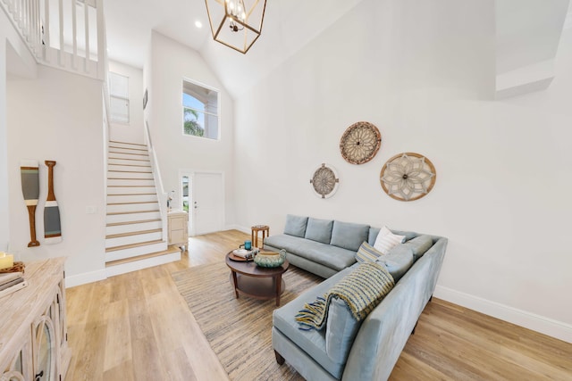 living room with light hardwood / wood-style floors, a high ceiling, and an inviting chandelier