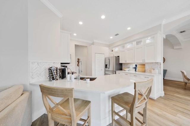 kitchen with backsplash, white cabinetry, sink, and stainless steel refrigerator with ice dispenser