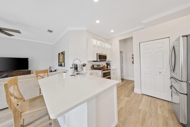 kitchen featuring white cabinetry, sink, stainless steel appliances, kitchen peninsula, and a breakfast bar area