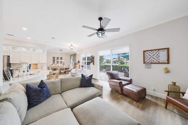 living room featuring light wood-type flooring, ceiling fan, and sink