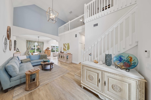 living room with a high ceiling, light hardwood / wood-style floors, and an inviting chandelier