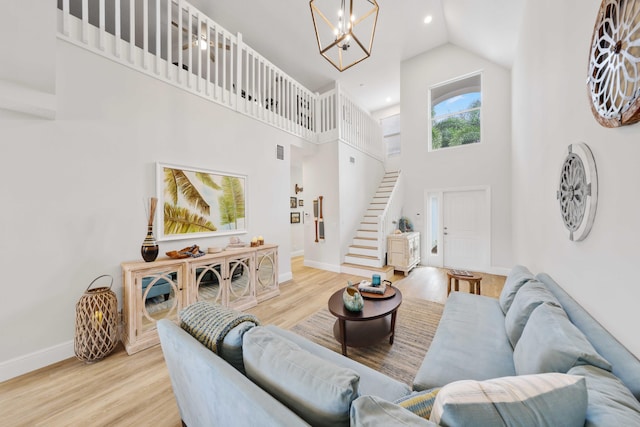 living room with a chandelier, a high ceiling, and light hardwood / wood-style floors