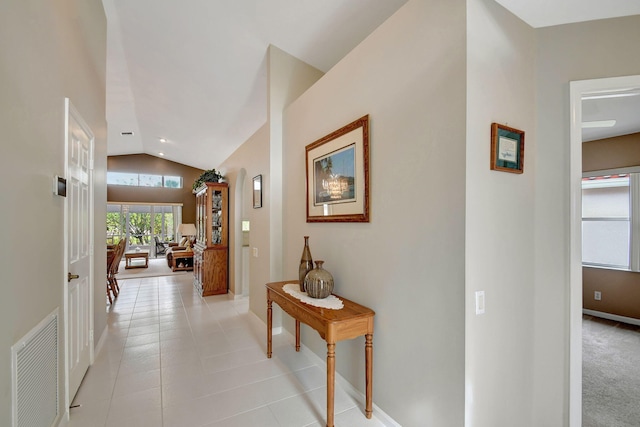 hallway with lofted ceiling and light tile patterned floors