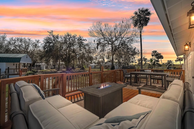 deck at dusk featuring an outdoor living space with a fire pit