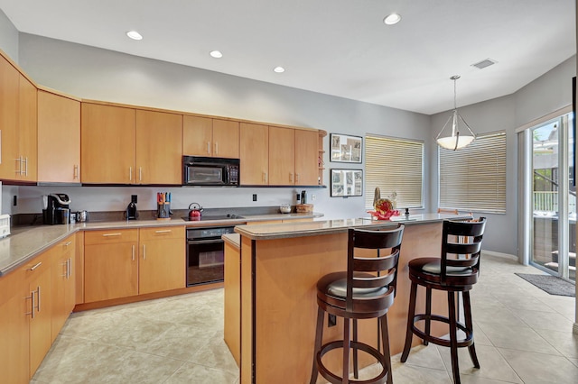 kitchen featuring pendant lighting, black appliances, light tile patterned floors, a kitchen island, and a breakfast bar area