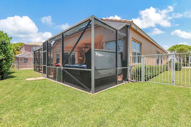 rear view of house featuring a lawn, glass enclosure, and ceiling fan