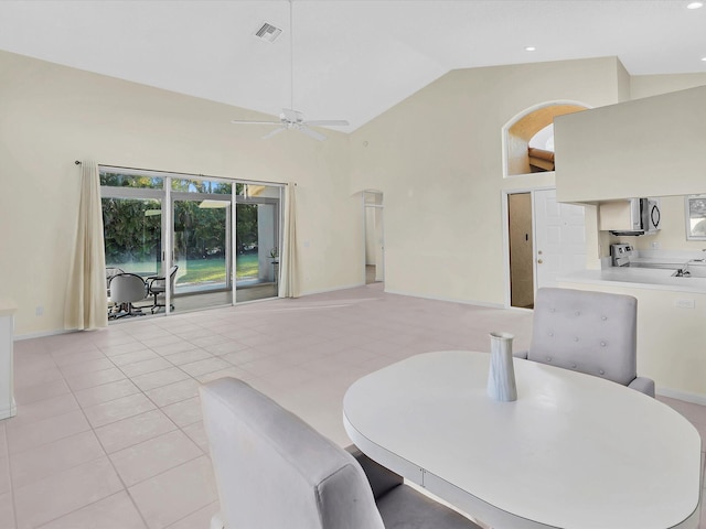 dining room featuring ceiling fan, light tile patterned flooring, and high vaulted ceiling