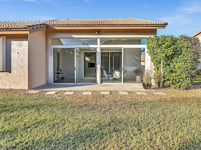 rear view of house featuring a sunroom and a lawn