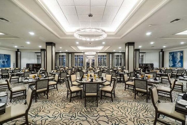 carpeted dining space with a chandelier, ornamental molding, and a tray ceiling