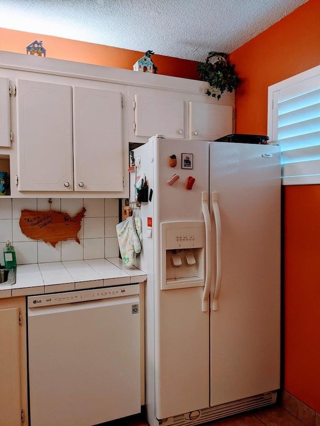 kitchen with white appliances, white cabinetry, and tasteful backsplash