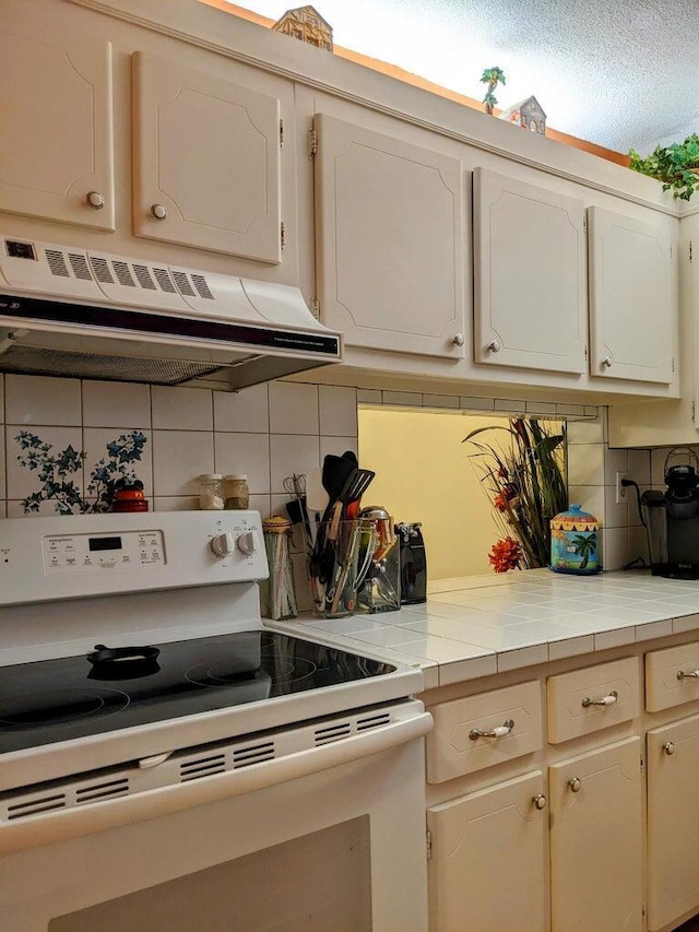 kitchen featuring white range with electric cooktop, decorative backsplash, and tile counters