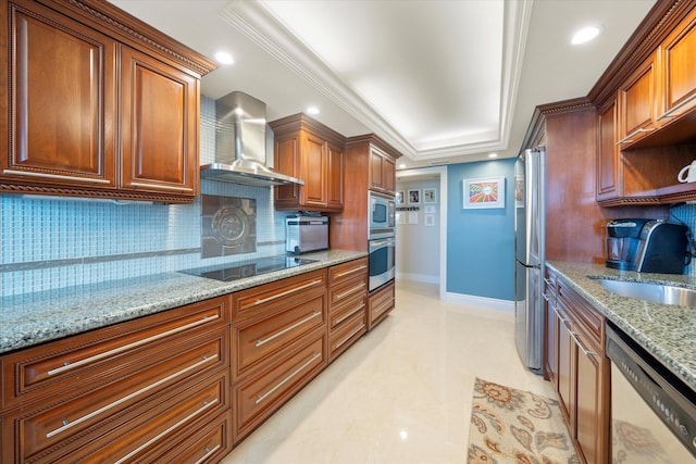 kitchen featuring light stone counters, ornamental molding, backsplash, wall chimney range hood, and appliances with stainless steel finishes