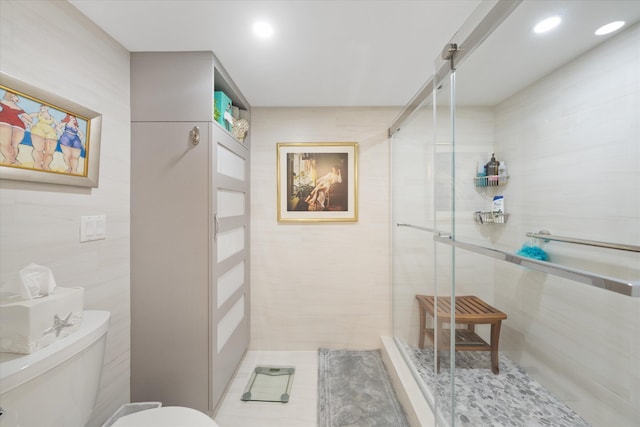 bathroom featuring tile walls, a shower with door, tile patterned floors, and toilet