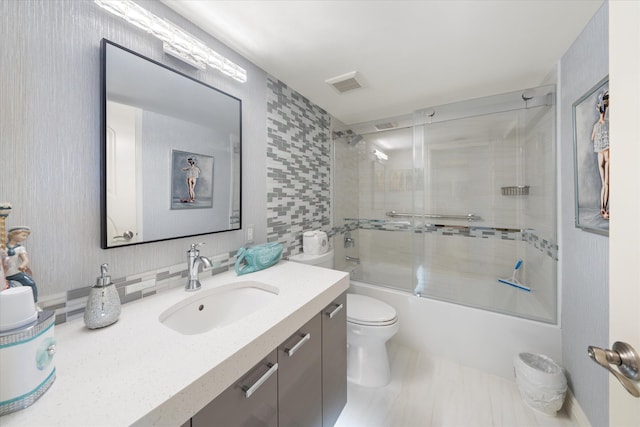 full bathroom with toilet, decorative backsplash, shower / bath combination with glass door, and vanity