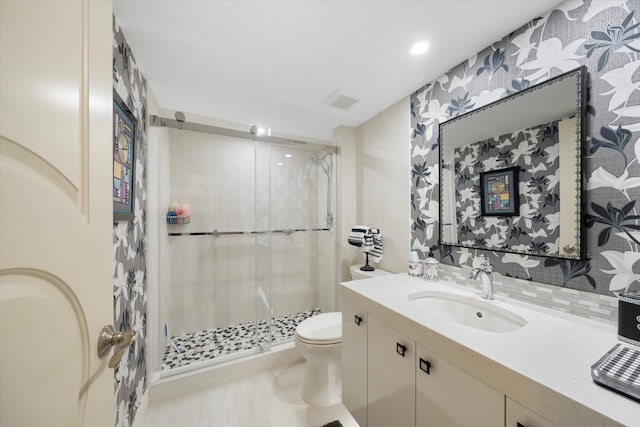 bathroom featuring toilet, a shower with door, and vanity